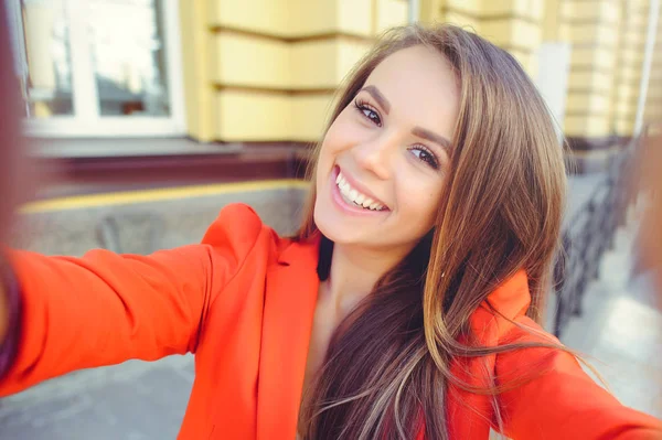 Moda bir bak, bir kırmızı ceket, sarı saçları açık havada şehir sıcak arka plan üzerinde giyen selfie, bir genç kadının yapması sıcak gün modeli