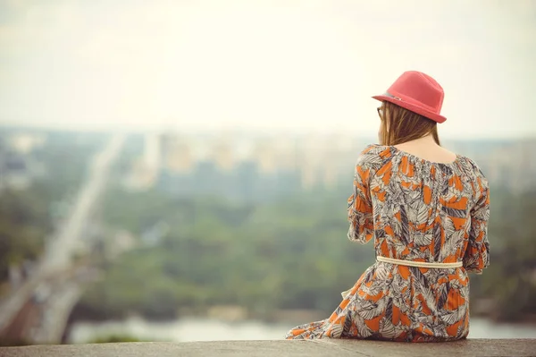 Κορίτσι σε ένα φόρεμα και το καπέλο που φαίνεται στην πόλη από ύψος — Φωτογραφία Αρχείου