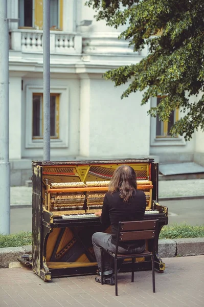 Street musician playing the old shabby piano — Stock Photo, Image