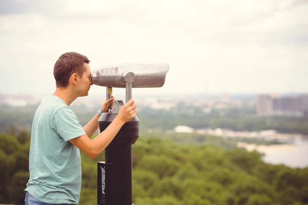 Tourist looks at the city through binoculars — Stock Photo, Image