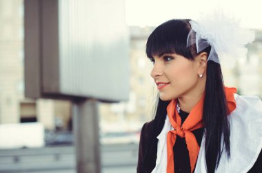 Güzel genç kadının saçlarını açık havada yapması. Mutlu ve sağlıklı Sovyet okul üniforması ve kırmızı kravat da giymiş. Güneşli gün. 