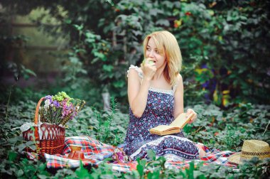Kırsal kesimde piknik güzel ve genç birbayan. Mutlu rahat gün açık havada. Açık. Gülümseyen kadın yeme elma, parkta rahatlatıcı. dinlenme ve sağlık
