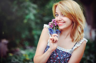 Kırsal kesimde piknik güzel ve genç birbayan. Mutlu rahat gün açık havada. Açık. Onun el parkta rahatlatıcı kır çiçekleri ile gülümseyen kadın. dinlenme ve sağlık