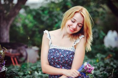 Kırsal kesimde piknik güzel ve genç birbayan. Mutlu rahat gün açık havada. Açık. Onun el parkta rahatlatıcı kır çiçekleri ile gülümseyen kadın. dinlenme ve sağlık