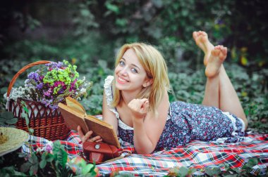 Kırsal kesimde piknik güzel ve genç birbayan. Mutlu rahat gün açık havada. Açık. Eller, Park'ta rahatlatıcı kitap ile gülümseyen kadın. rekreasyon