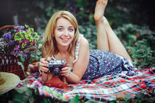 Mulher bonita fazendo um piquenique no campo. Feliz dia aconchegante ao ar livre. Abre. Mulher sorridente com câmera nas mãos, relaxando no parque. recreação — Fotografia de Stock