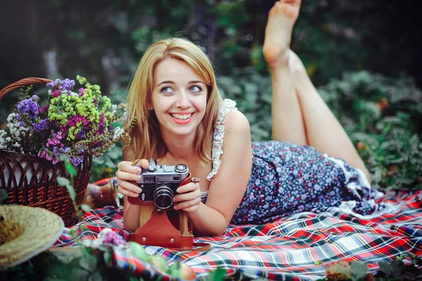 Mulher bonita fazendo um piquenique no campo. Feliz dia aconchegante ao ar livre. Abre. Mulher sorridente com câmera nas mãos, relaxando no parque. recreação — Fotografia de Stock