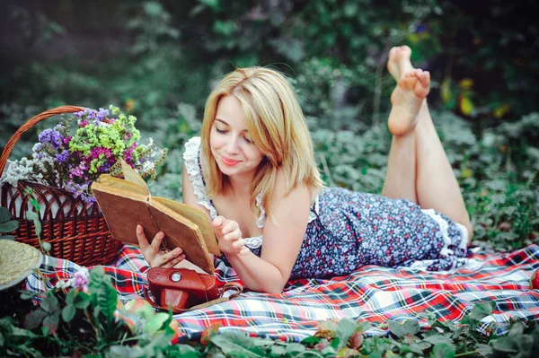 美丽的年轻女子在乡下野餐。户外快乐的一天。打开。微笑的女人, 手里拿着书, 在公园里放松。娱乐 — 图库照片