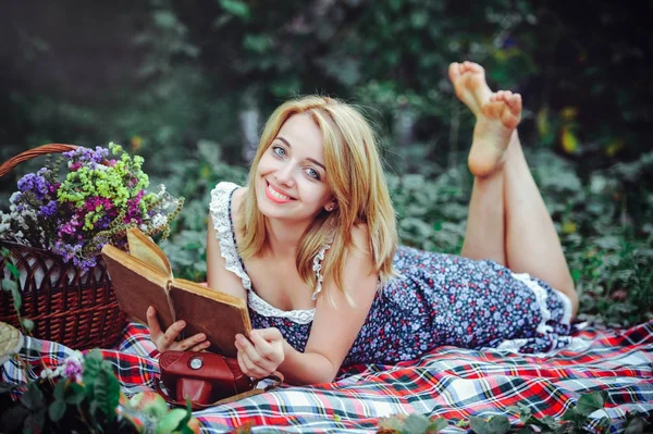 Schöne junge Frau beim Picknick auf dem Land. glücklicher gemütlicher Tag im Freien. Offen. Lächelnde Frau mit Buch in der Hand, entspannt im Park. Erholung — Stockfoto