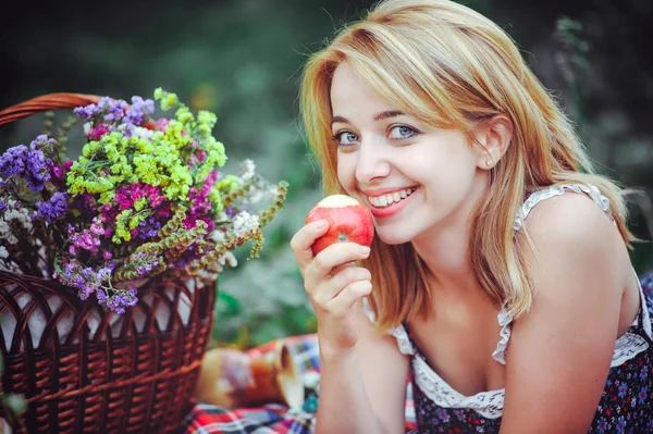 美丽的年轻女子在乡下野餐。户外快乐的一天。打开。微笑的女人吃苹果, 在公园里放松。休息和健康 — 图库照片