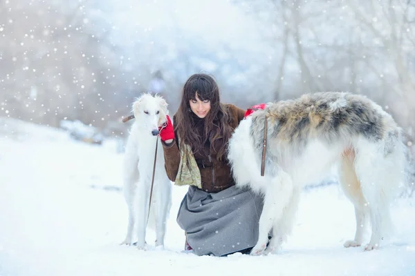 Christmas walk. Beautiful surprised woman in winter clothes with greyhound dogs graceful winter background with snow, emotions. portrait of a woman. New Year — Stock Photo, Image