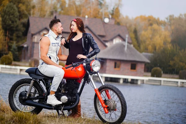 Стильная и модная влюбленная пара на мотоцикле, флиртующая крупным планом на фоне поздней осени в парке — стоковое фото