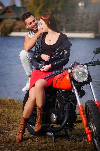 Stijlvolle en trendy paar verliefd op een close-up motorfiets flirten op een achtergrond van de late herfst in het park — Stockfoto