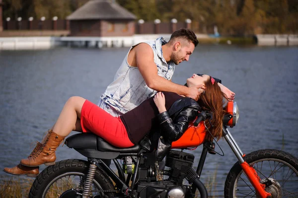Стильная и модная влюбленная пара на лежащем мотоцикле, флиртующая крупным планом на фоне поздней осени в парке — стоковое фото