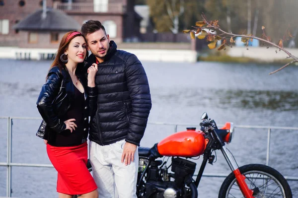 Elegante e moderno casal apaixonado em uma motocicleta flertando close-up em um fundo do final do outono no parque — Fotografia de Stock