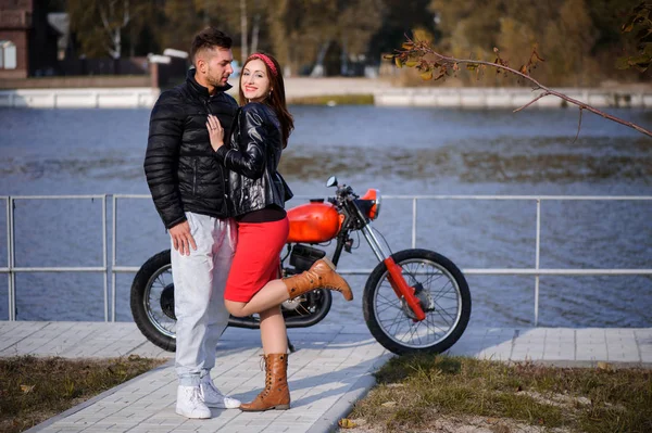 Stijlvolle en betaalbare paar verliefd op een close-up motorfiets flirten op een achtergrond van de late herfst in het park — Stockfoto