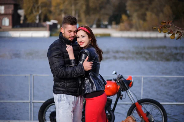 Elegante e moderno casal apaixonado em uma motocicleta flertando close-up em um fundo do final do outono no parque — Fotografia de Stock