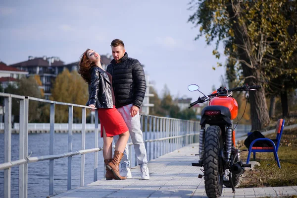 Stylish and trendy couple in love on a motorcycle flirting close-up on a background of late autumn in the park — Stock Photo, Image