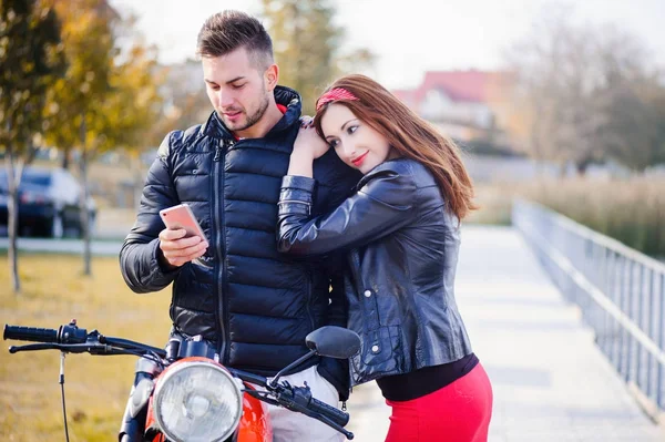 Elegante e moderno casal apaixonado em uma motocicleta flertando close-up em um fundo do final do outono no parque — Fotografia de Stock