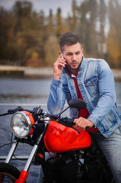 Stylish and trendy sports man talking on the phone close-up on a background of late autumn in the park — Stock Photo, Image