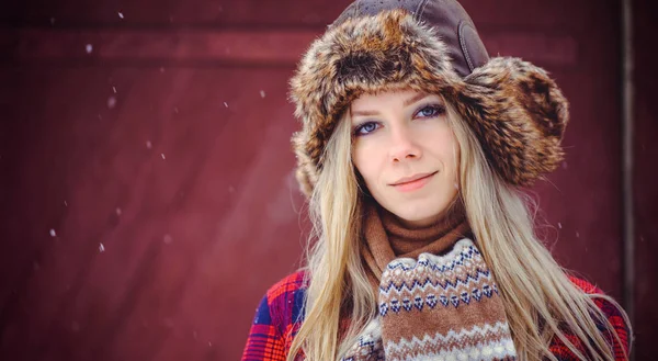 Tierna mujer en un sombrero de invierno y varillas sobre un fondo rojo, un tiro de publicidad brillante —  Fotos de Stock