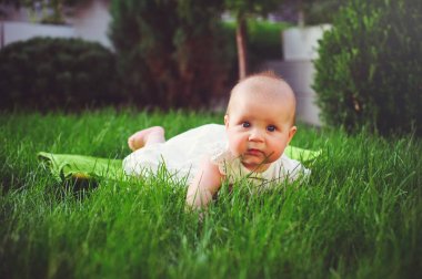 yarı yaşındaki çocuk gezinmeler beyaz elbise giymiş bahçedeki çimlerin üzerine sevinir, 6 ay. Çocukların, çocuk mal kavram eğitimi