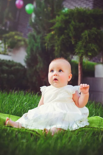 Půl letý dítě sedět na trávě ve dvoře, oblečené v bílých šatech raduje, 6 měsíců. Koncepce vzdělávání dětí, Dětské zboží — Stock fotografie