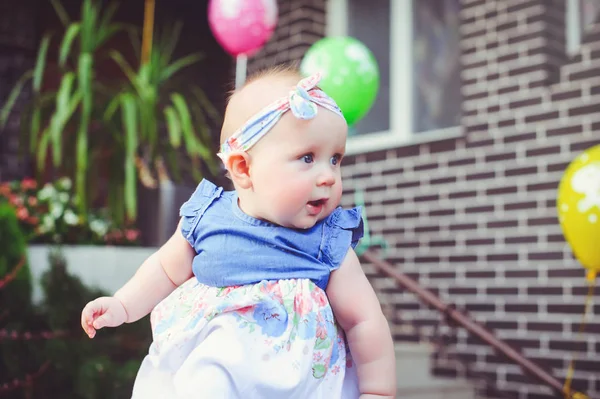 Porträtt av ett sex månader gammalt barn jublar, är klädd i en blå klänning och ett pannband, 6 månader. Begreppet utbildning av barn, barns varor — Stockfoto