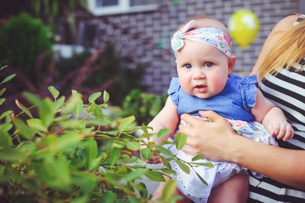 Le portrait d'un enfant de six mois se réjouit, est vêtu d'une robe bleue et d'un bandage sur la tête, mère de 6 mois a sur les mains. L'éducation conceptuelle des enfants, les biens des enfants — Photo