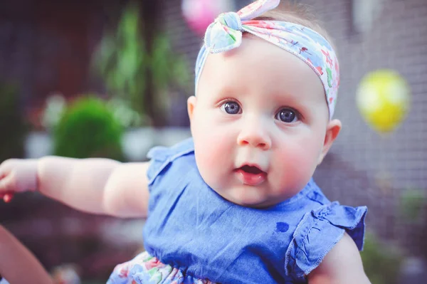 Het portret van een zes-maand-oude kind verheugt, is gekleed in een blauwe jurk en een hoofdband, 6 maanden. Concept onderwijs voor kinderen, kinderen van goederen — Stockfoto