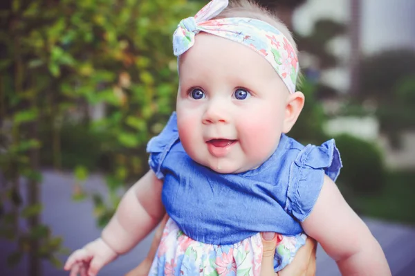 Портрет полугодовалого ребенка радуется, одет в голубое платье и повязку, 6 месяцев. Концепция воспитания детей, товаров для детей — стоковое фото