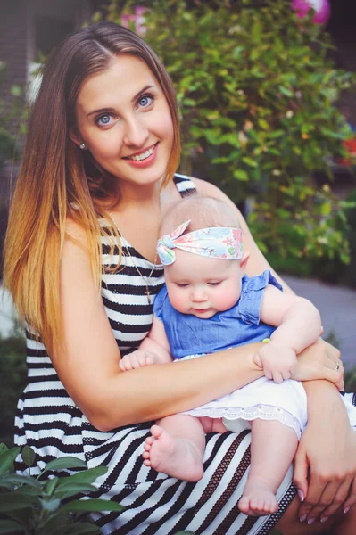 Portrait d'une femme heureuse avec un bébé suceur assis, mère tenant sa fille dans ses bras se réjouissant dans une maison de campagne, concept d'élever des enfants, enfance — Photo