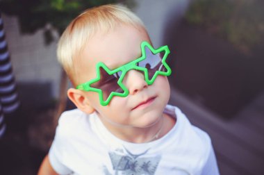 gözlük yıldız ile mutlu sarışın çocuk kamera gülümseyen içine bakar. yumuşak sıcak tonlama