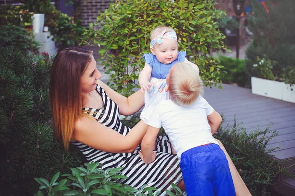 Woman mother with two young children lie on a green lawn, entertain the girl, the concept of motherhood and the upbringing of children — Stock Photo, Image