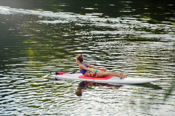 Молодая спортсменка занимается фитнесом на доске с веслом на озере — стоковое фото