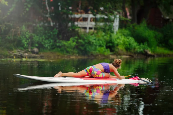 Junge athletische Frau beim Fitnesstraining auf einem Brett mit einem Ruder auf einem See — Stockfoto