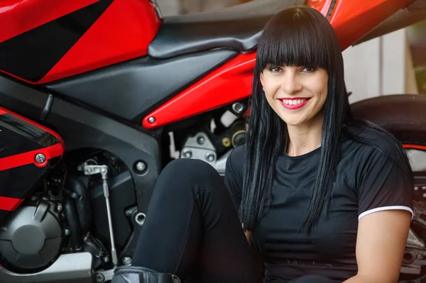 Egy motoros lány fekete ruhában a jelentő ülve a város sport motorkerékpár — Stock Fotó