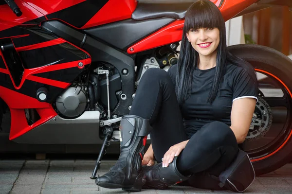 都市に座ったポーズのスポーツ バイクで黒い服を着たバイカーの女の子 — ストック写真