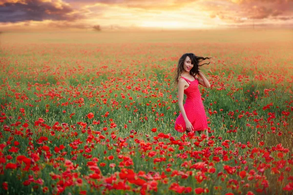 Красивая женщина в красном платье в маковом поле на закате трепещут волосы, теплый тонинг, счастье и здоровый образ жизни — стоковое фото