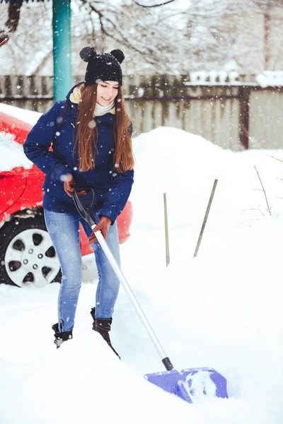 Winterporträt einer jungen Frau beim Schneeräumen. Schönheit freudige Model Mädchen lachen und Spaß mit einer Schaufel. schöne junge Frau im Freien — Stockfoto