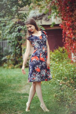 Gülümseyen genç esmer kadın bir elbise onun yurdunda avlusunda poz sevinir, mutlu kaygısız