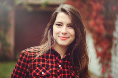 Gülümseyen genç esmer kadın onu ikamet kırmızı Kareli gömlekli avlusunda poz mutlu portre rahat sesleri mutlu kaygısız, sağlık