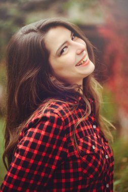 Gülümseyen genç esmer kadın onu ikamet kırmızı Kareli gömlekli avlusunda poz mutlu portre rahat sesleri mutlu kaygısız, sağlık