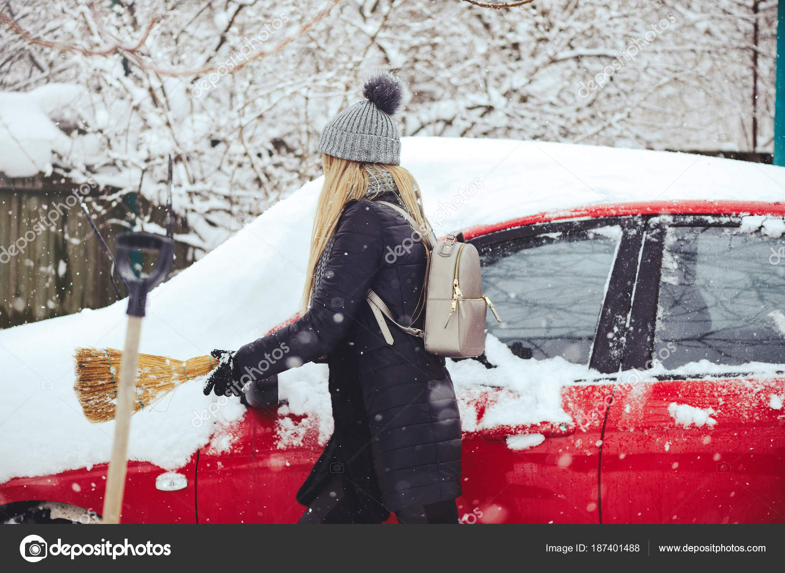 Frau, die schnee von einem auto mit einem besen entfernt