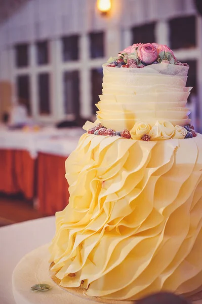 Un pastel de boda de varios niveles beige en una celebración en un interior acogedor —  Fotos de Stock