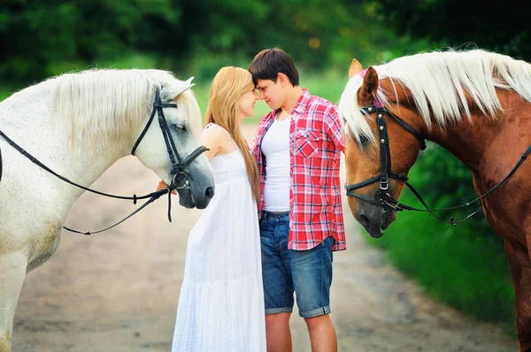 Krásný milující pár s koňmi stojí v lese na silniční, útulný a teplý umělecký obraz, létající jasný den — Stock fotografie
