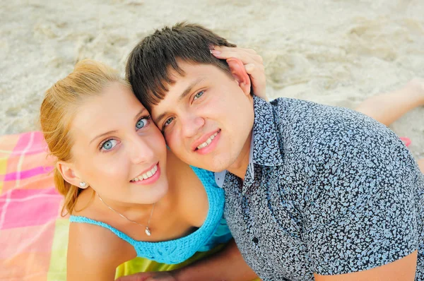 Feliz pareja amorosa en un día soleado brillante yacen en la playa, rubia de ojos azules — Foto de Stock