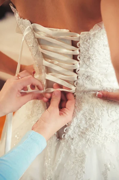 Jurk van de bruid hand en close-up vetersluiting, warm en gezellig beeld — Stockfoto