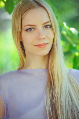 Çekici mütevazı kızı sarışın dren saç ve mor elbise açık havada, hassasiyet ve yumuşaklık doğa arka plan üzerinde doğal makyaj