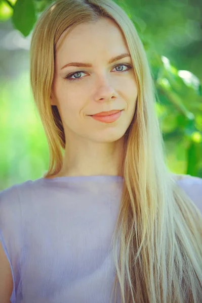 Atrakcyjne skromna młoda dziewczyna z dr blond włosy i makijaż naturalny w fioletowa sukienka na zewnątrz, czułość i delikatność na tle przyrody — Zdjęcie stockowe